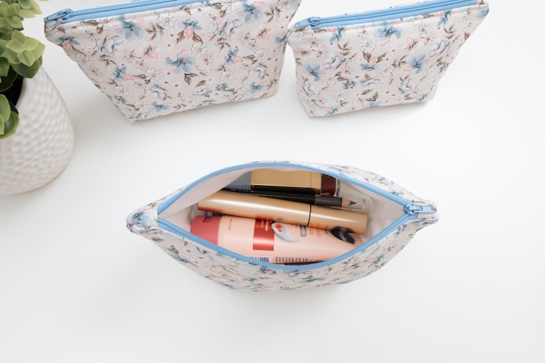 Floral zip pouch opened and filled with makeup and lip products, showing everyday use and size.