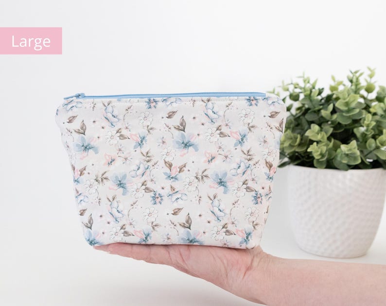Large floral zip pouch held in one hand beside a potted plant, labelled Large.