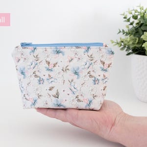 Small floral zip pouch held in one hand beside a potted plant, labelled Small.
8. Medium size card