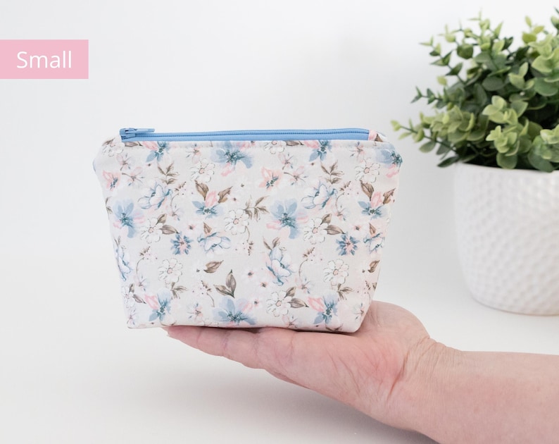 Small floral zip pouch held in one hand beside a potted plant, labelled Small.
8. Medium size card