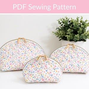 May include: Three floral print cosmetic bags in varying sizes with gold zippers. The bags are white with a pattern of small pink, blue, and yellow flowers. The text "PDF Sewing Pattern" is at the top.