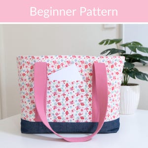 Peut inclure: Un sac fourre-tout avec un motif floral dans des tons de rose, rouge et bleu, doté d'une base en jean bleu foncé et de sangles en tissu rose uni. Le sac comprend une poche avant contenant une carte rectangulaire blanche. Le texte "Beginner Pattern" est visible.