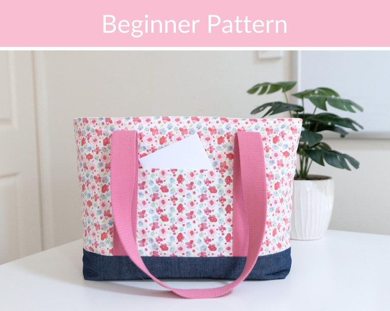 Puede incluir: Un bolso tote con estampado floral en tonos rosa, rojo y azul, con una base de mezclilla azul oscuro y correas de tela rosa s&oacute;lido. El bolso incluye un bolsillo frontal que contiene una tarjeta rectangular blanca. El texto "Beginner Pattern" es visible.