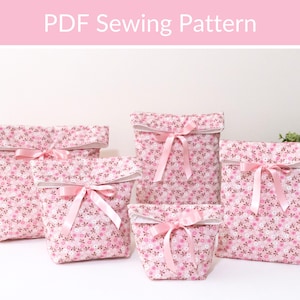May include: Five fabric gift bags in varying sizes, each with a pink floral pattern and a matching pink ribbon bow. The bags have a white folded-over top edge. The text "PDF Sewing Pattern" is at the top of the image.