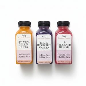 May include: Three bottles of sulfate-free bubble bath with black caps. The bottles contain different colored liquids: orange, purple, and red. Each bottle has a label with a unique scent name: Oatmeal Milk N Honey, Black Raspberry Vanilla, and A Thousand Dreams. Each bottle is 226 g.
