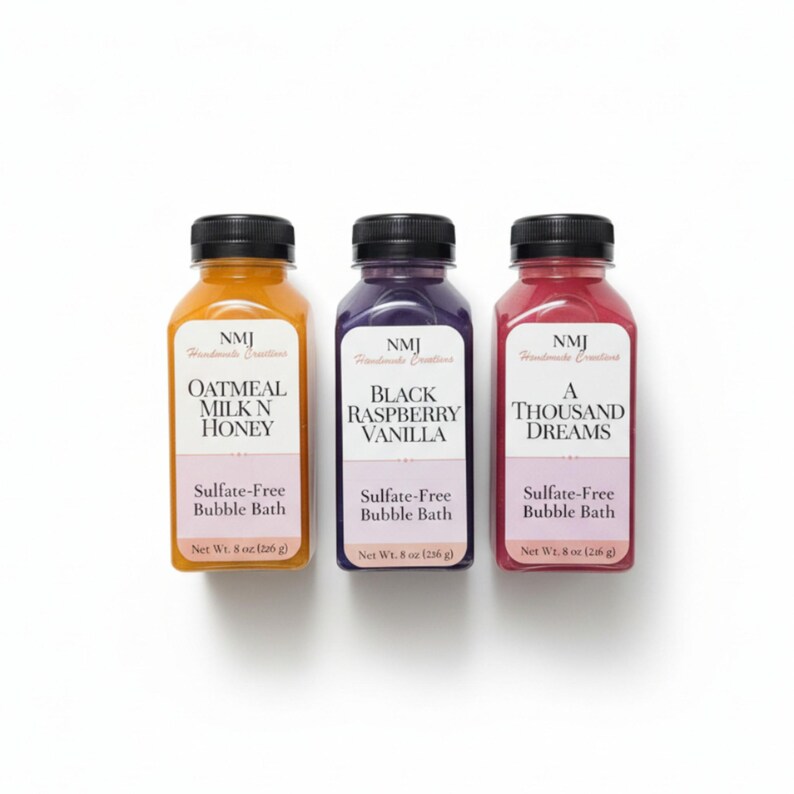 May include: Three bottles of sulfate-free bubble bath with black caps. The bottles contain different colored liquids: orange, purple, and red. Each bottle has a label with a unique scent name: Oatmeal Milk N Honey, Black Raspberry Vanilla, and A Thousand Dreams. Each bottle is 226 g.