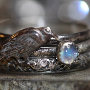 Puede incluir: Un anillo de plata con un dise&ntilde;o de p&aacute;jaro y una piedra de luna. El anillo est&aacute; hecho de cuatro bandas.
