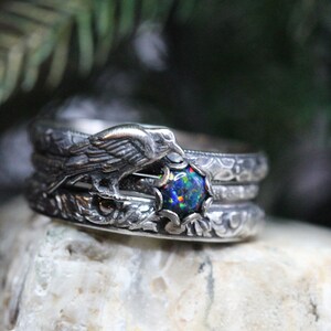 Puede incluir: Un anillo de plata con una piedra de &oacute;palo negro y un dise&ntilde;o de p&aacute;jaro detallado. El anillo est&aacute; apilado con otras dos bandas de plata.
