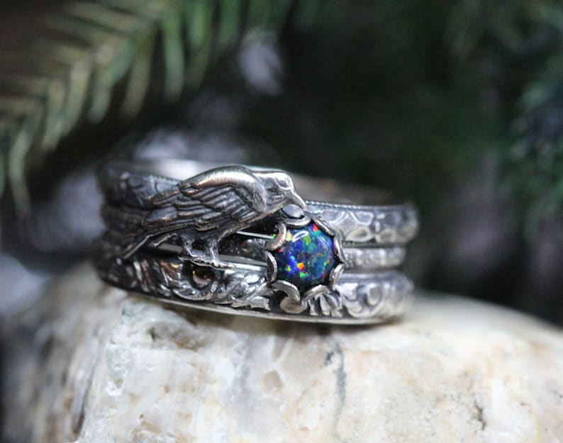 Puede incluir: Un anillo de plata con una piedra de &oacute;palo negro y un dise&ntilde;o de p&aacute;jaro detallado. El anillo est&aacute; apilado con otras dos bandas de plata.