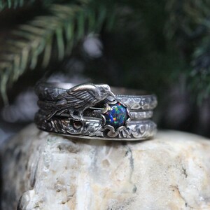 Puede incluir: Un anillo de plata con una piedra de &oacute;palo negro y un dise&ntilde;o de p&aacute;jaro detallado. El anillo est&aacute; formado por tres bandas.