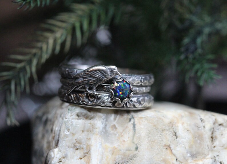Puede incluir: Un anillo de plata con una piedra de &oacute;palo negro y un dise&ntilde;o de p&aacute;jaro detallado. El anillo est&aacute; formado por tres bandas.