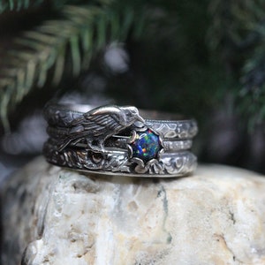 Puede incluir: Un anillo de plata con una piedra de &oacute;palo negro y un dise&ntilde;o de p&aacute;jaro detallado. El anillo est&aacute; formado por tres bandas.
