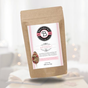 Puede incluir: Una bolsa de papel marrón de té Ripe & Ready de Birds & Bees Teas. La etiqueta presenta un diseño rosa y blanco con el logotipo de la marca y texto. La mezcla de té incluye hoja de frambuesa roja, canela, pimienta de Jamaica e hibisco. Peso neto 141g.