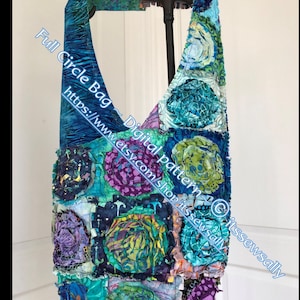 Puede incluir: Una bolsa de tela azul y verde con un diseño floral. La bolsa está hecha de tela de patchwork y tiene un aspecto único y hecho a mano. La bolsa está colgada de un soporte negro. El texto "Full Circle Bag - Digital pattern © itsewssally https://www.etsy.com/shop/itsewssally" está impreso en la bolsa.