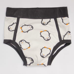 May include: White underwear with a repeating pattern of cartoon penguins with black and white bodies and orange feet. The waistband and trim are dark gray. The underwear is made of a soft, comfortable material.