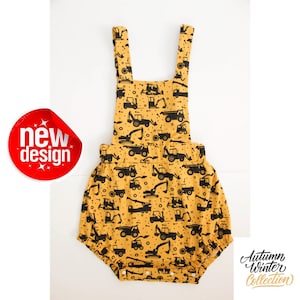 May include: A yellow baby romper with black construction vehicle silhouettes. The romper has straps and a ruffled bottom. The text "Autumn Winter Collection" is visible in the bottom right corner.
