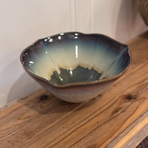 May include: A ceramic bowl with a scalloped rim featuring a gradient glaze that transitions from a deep dark blue at the top edge to a creamy off-white in the centre, with a dark blue base interior and a smooth, rounded, wide-mouthed basin shape.