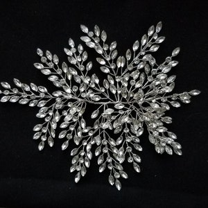 May include: A silver hair comb with a delicate design of crystal leaves. The comb is perfect for adding a touch of sparkle to any hairstyle.