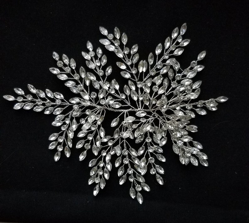May include: A silver hair comb with a delicate design of crystal leaves. The comb is perfect for adding a touch of sparkle to any hairstyle.