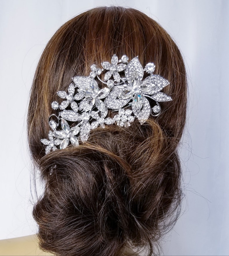 Puede incluir: Peine de pelo plateado con un dise&ntilde;o floral con brillantes transparentes. El peine se lleva en el pelo de una mujer.