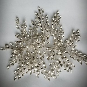 May include: Silver bridal hair comb with a delicate design of crystal leaves and branches. The comb is perfect for adding a touch of sparkle to any hairstyle.