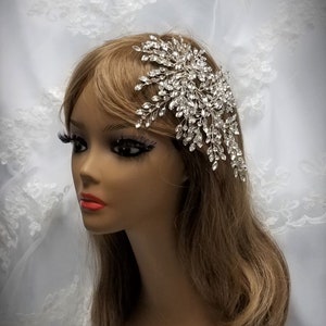 May include: A silver bridal hair comb with crystal rhinestones. The comb is designed in a cascading, floral pattern.