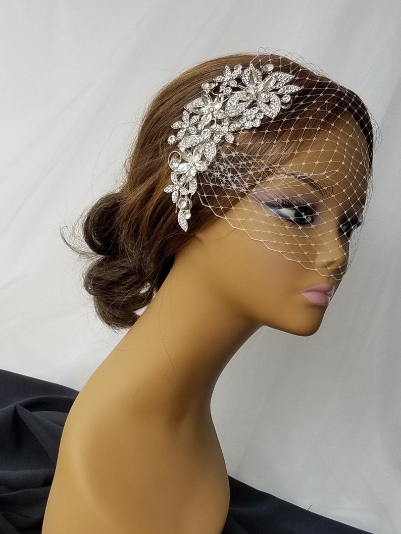 Puede incluir: Un velo de novia blanco con un peine de pelo floral plateado adornado con diamantes de imitaci&oacute;n. El velo est&aacute; hecho de una red delicada y est&aacute; dise&ntilde;ado para ser usado en el lado de la cabeza.
