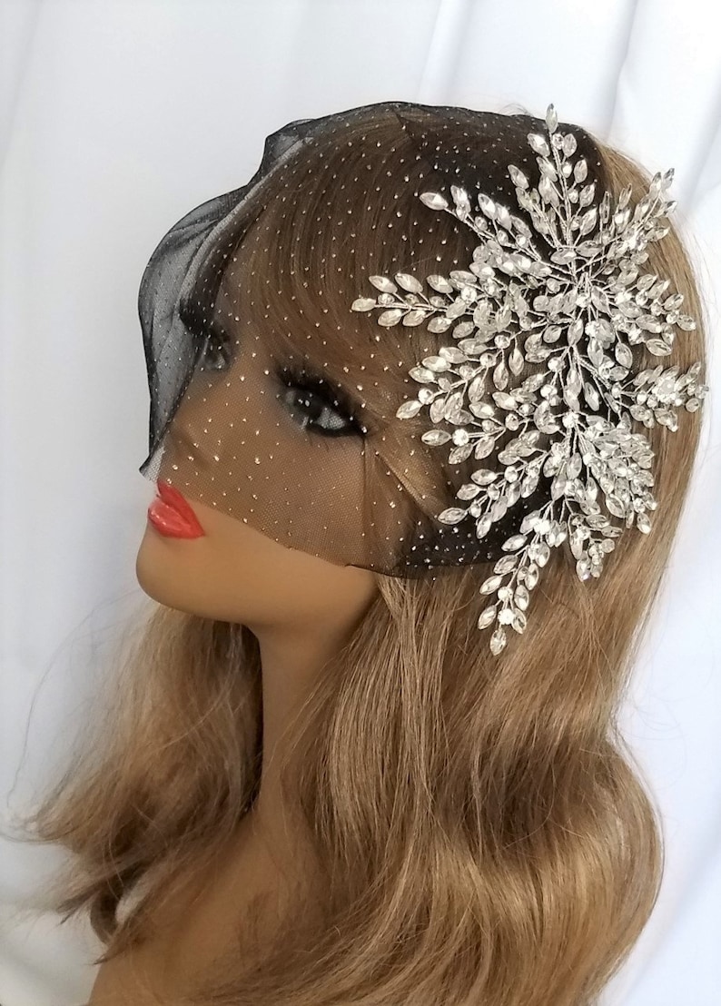 May include: A black bridal veil with a sparkly design and a large silver rhinestone floral hair comb.