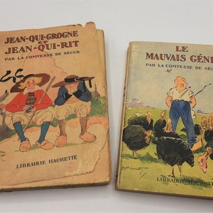 Puede incluir: Dos libros infantiles vintage con cubiertas ilustradas. El libro de la izquierda se titula "Jean-Qui-Grogne et Jean-Qui-Rit" de La Comtesse de Ségur. El libro de la derecha se titula "Le Mauvais Génie" de La Comtesse de Ségur. Ambos libros tienen las palabras "Librairie Hachette" impresas en la parte inferior.