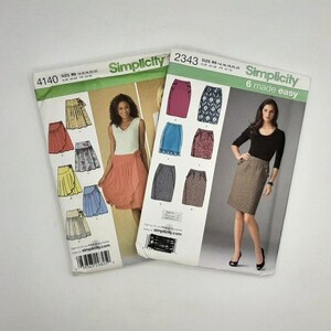 May include: Two Simplicity sewing patterns for skirts. The pattern on the left is number 4140 and features a variety of wrap skirts. The pattern on the right is number 2343 and features a variety of pencil skirts. The text "6 made easy" is printed on the right pattern.