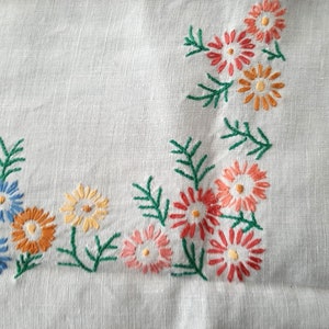 May include: White linen tablecloth with embroidered floral designs in shades of blue, orange, pink, and green.