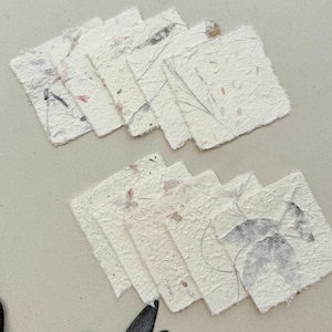 Op de afbeelding: Een set van drie keramische mokken met een gespikkelde, matte afwerking. De mokken zijn in crème, lichtgrijs en donkergrijs. Elke mok heeft een eenvoudig, minimalistisch ontwerp en een afgeronde handgreep.