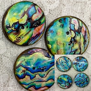 May include: Assortment of six iridescent abalone shell buttons with a wood backing. The buttons have a variety of blue, green, yellow, and pink colours.