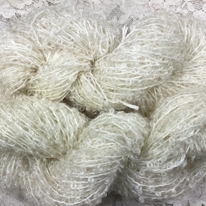May include: A skein of white yarn with a fluffy, curly texture.