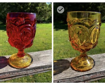 Könnte beinhalten: Ein Set aus vier Glasbechern mit einem erhabenen Mond- und Sternmuster auf der Kuppa. Die Kollektion umfasst einen grünen, einen roten, einen bernsteinfarbenen und einen blauen Becher, die jeweils auf einem runden Fuß mit kurzem, dickem Stiel stehen.