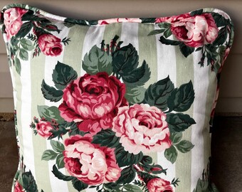 Könnte beinhalten: Ein weißes Kissen mit grünen Streifen und einem Blumenmuster aus rosa und roten Rosen. Das Kissen hat einen weißen Hintergrund mit grünen Streifen und einem Blumenmuster aus rosa und roten Rosen.