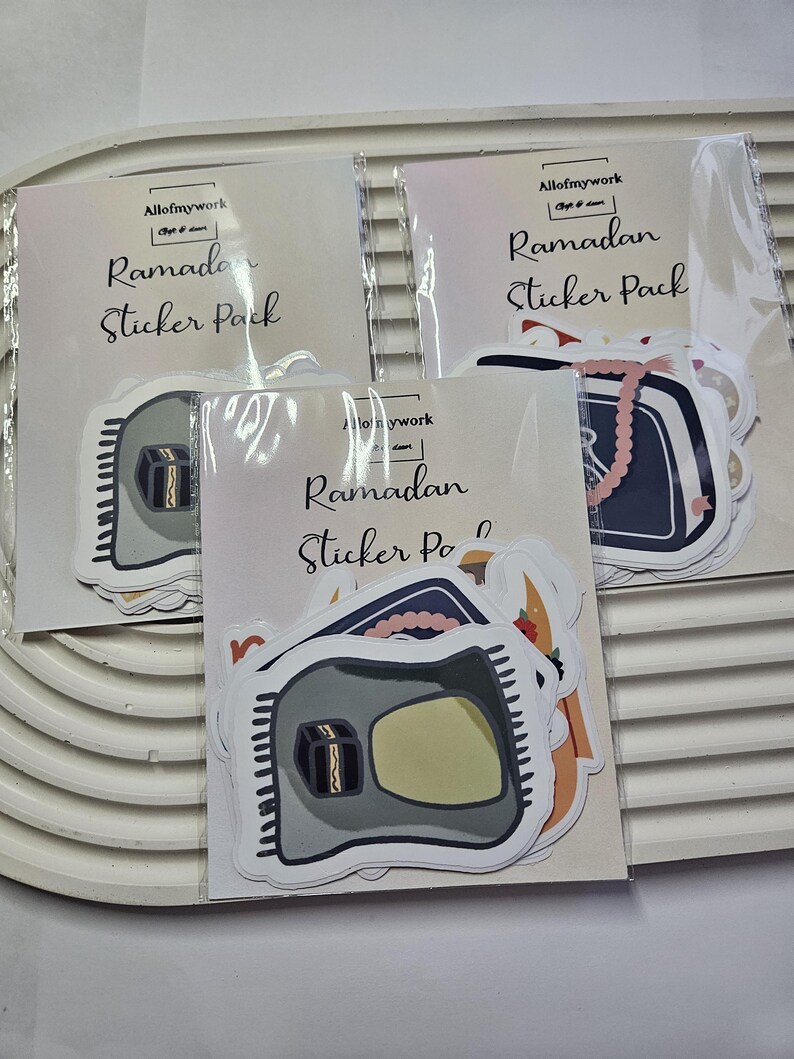 May include: Three packs of Ramadan sticker packs. Each pack has a different design featuring a mosque, a prayer rug, and a book with a tassel. The text on the packs reads "Allofmywork Ramadan Sticker Pack".
