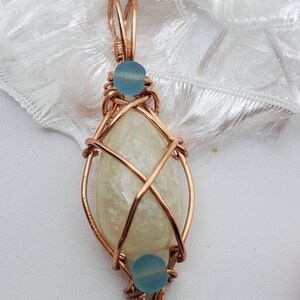 Teardrop shaped white resin pendant and blue sea glass beads, wrapped with copper wire