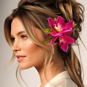 May include: A woman with long, brown hair styled in a messy bun with a pink orchid flower hair clip.