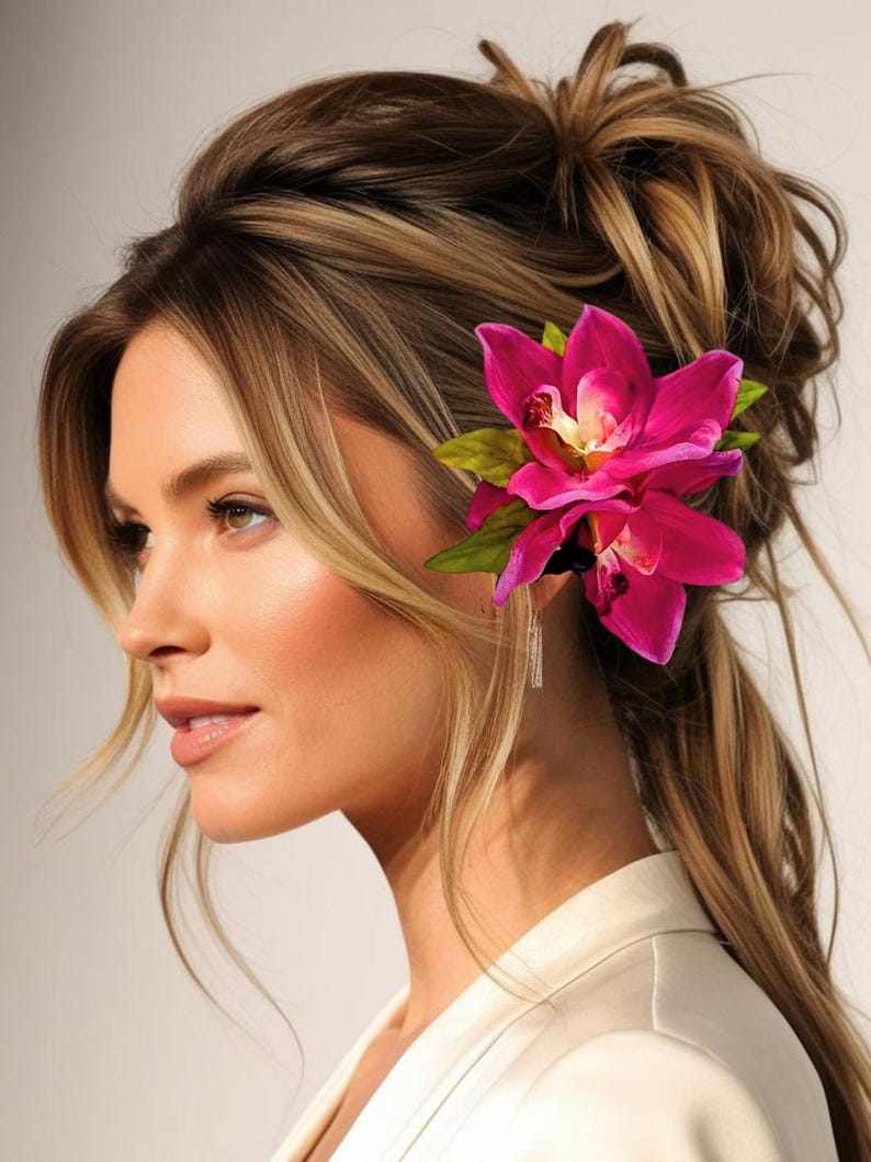 May include: A woman with long, brown hair styled in a messy bun with a pink orchid flower hair clip.