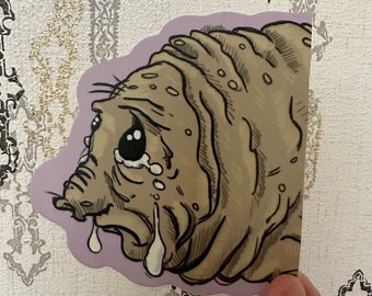 May include: A sticker featuring a cartoon illustration of a crying, light brown water bear with black outlines. The sticker has a purple border and is on a patterned background.