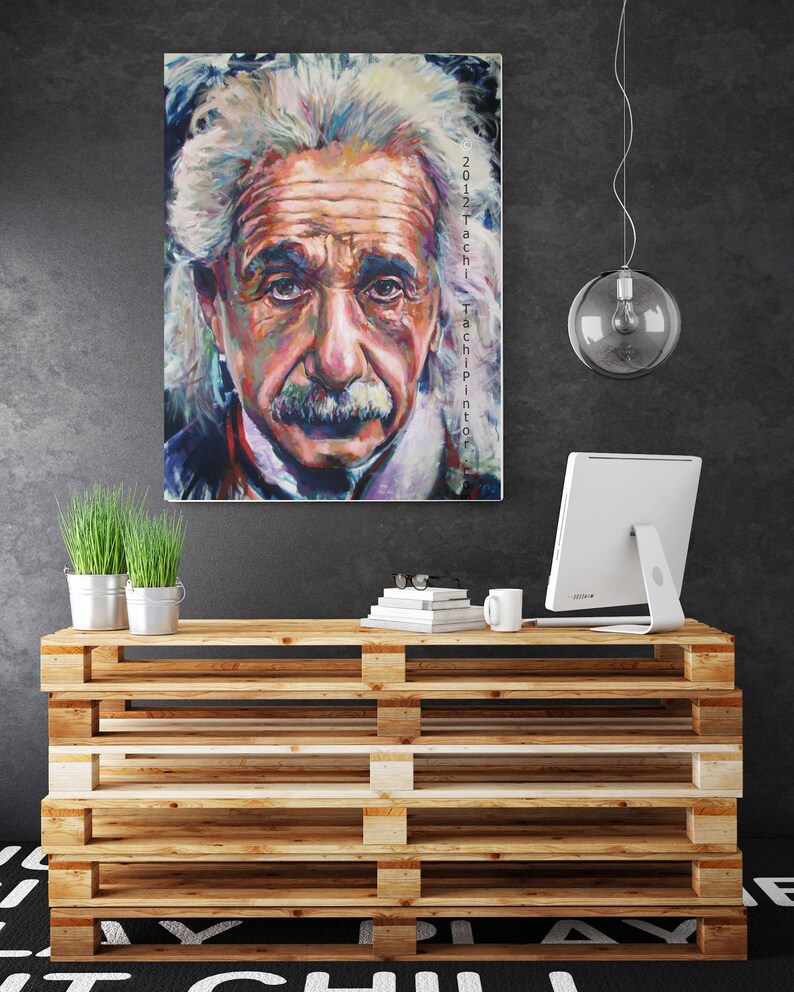 May include: A colorful portrait of Albert Einstein with text on the side. The artwork is displayed above a wooden pallet-style cabinet. The cabinet holds a computer monitor, books, a mug, and small potted plants.
