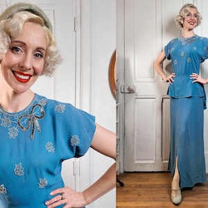 Könnte beinhalten: Ein blaues Kleid im Vintage-Stil mit passendem Oberteil und Rock. Das Oberteil hat einen dekorativen, mit Perlen besetzten Kragen und eine Schleife. Das Kleid wird mit einem passenden Stirnband getragen. Das Outfit erinnert an die 1940er Jahre. Das Kleid hat einen Seitenschlitz.