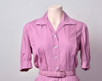 May include: A pink button-up dress with a collared neckline and a belt. The dress has short sleeves and a pleated skirt.