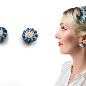 Könnte beinhalten: Ein Paar blaue und weiße Ohrringe in Blumenform. Die Ohrringe bestehen aus kleinen, weißen Perlen und blauem Stoff. Die Ohrringe werden von einer Frau mit blonden Haaren getragen.