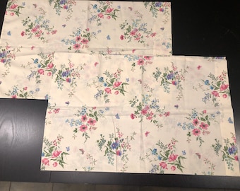 May include: Two cream-colored pillowcases with a floral pattern featuring pink, blue, and green flowers.