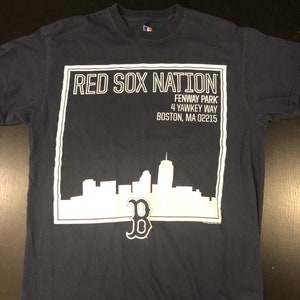 May include: A navy blue t-shirt with a white graphic of the Boston skyline and the text "RED SOX NATION" with the address "Fenway Park, 4 Yawkey Way, Boston, MA 02215". The graphic also includes a white Boston Red Sox "B" logo.