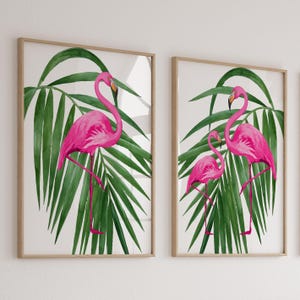 Pode incluir: Duas impressões artísticas emolduradas com ilustrações em aquarela de flamingos cor-de-rosa com folhas de palmeira verdes. Os flamingos são retratados em um ambiente tropical, com uma perna levantada. As molduras são de cor castanho claro.