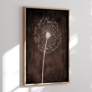 May include: Framed art print featuring a white dandelion seed head against a dark brown textured background. The dandelion is depicted in a minimalist style with a long stem. The frame is a natural wood color.