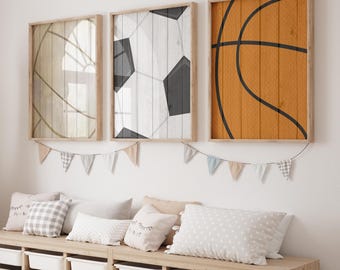 May include: Three framed wood prints of sports balls on a white wood background. The prints feature a basketball, a soccer ball, and a volleyball. The prints are hanging on a white wall above a wooden bench with pillows.